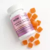 White bottle with orange gummies scattered around, labeled for menstrual pain relief.