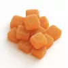 Orange gummy candies piled together on a white surface.