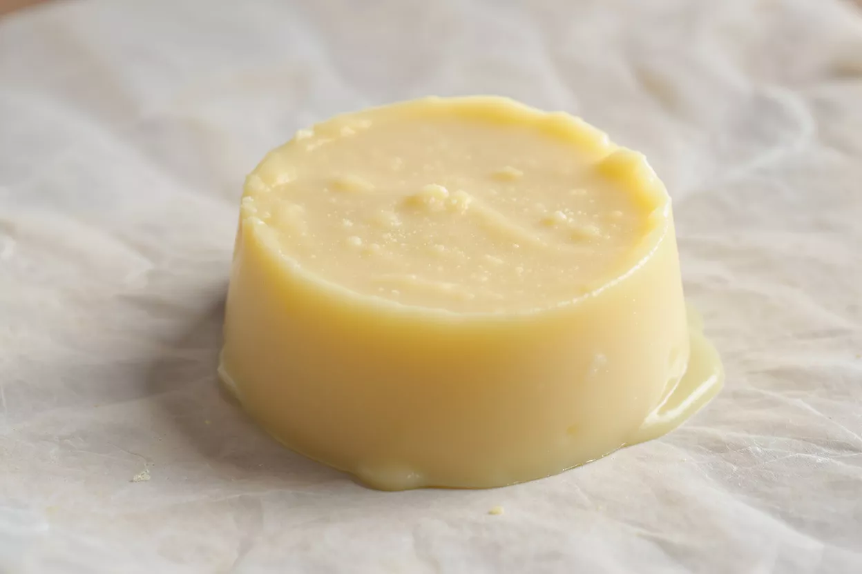 A round mold of pale yellow pastry cream sitting on crumpled parchment paper.