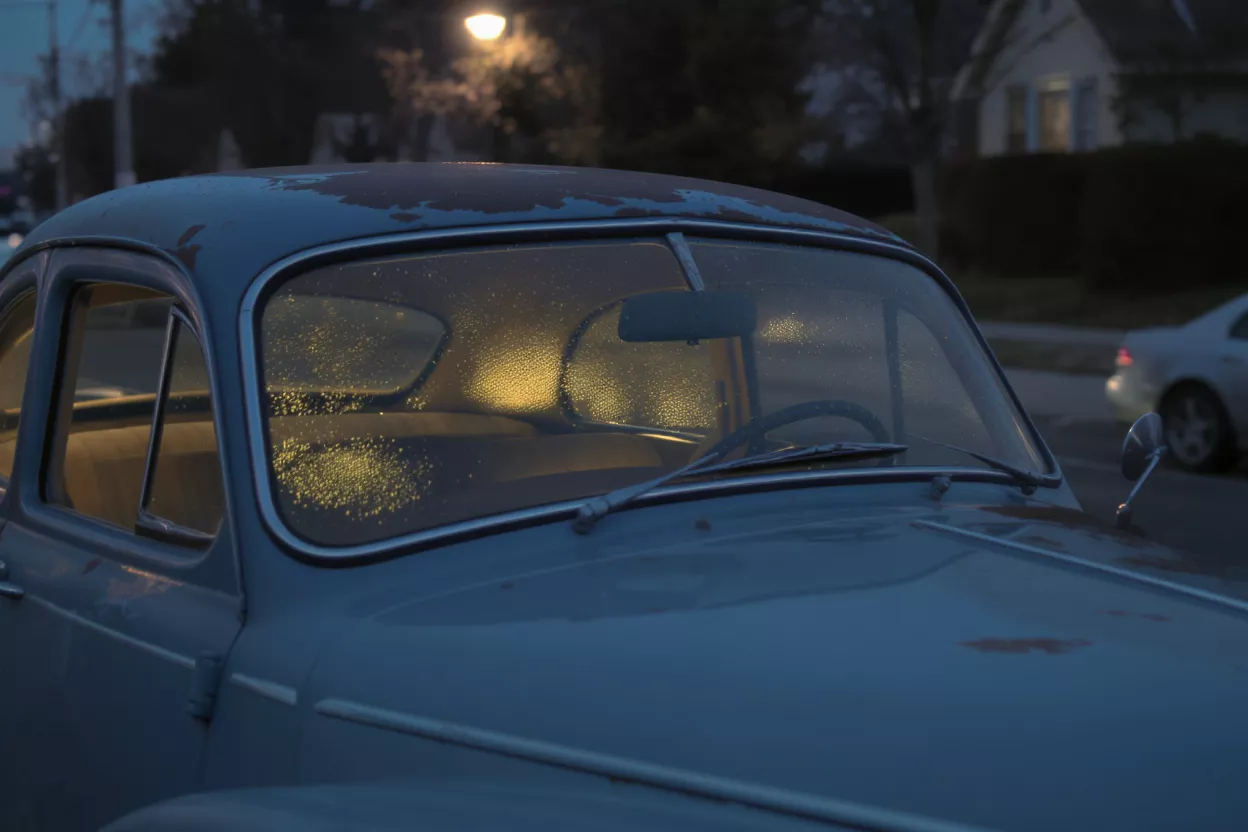 Old blue car with foggy windows at night