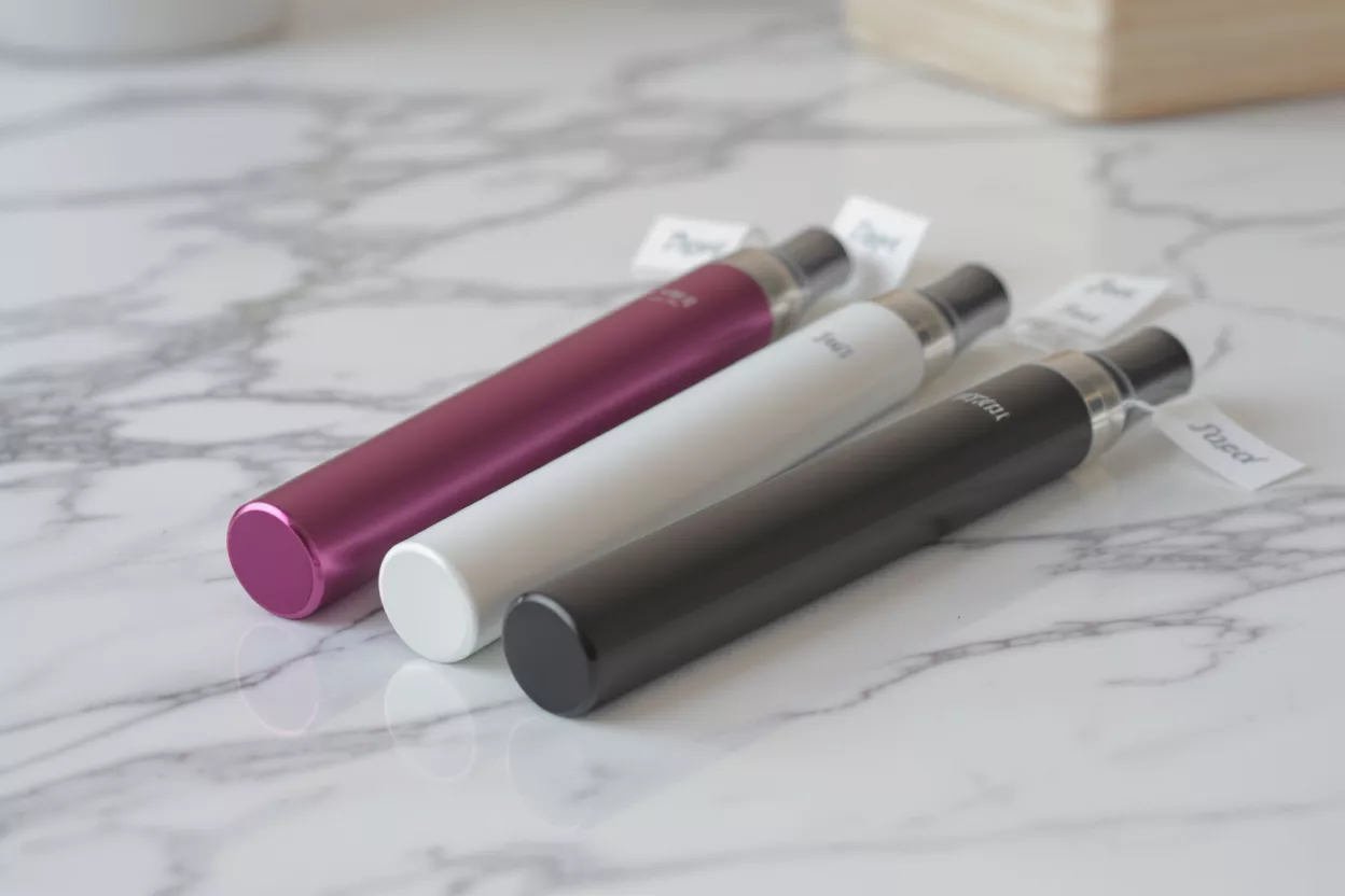 Stylos Vape Élégants en Trois Couleurs Trois stylos vape en magenta, blanc et noir sur une surface en marbre blanc.