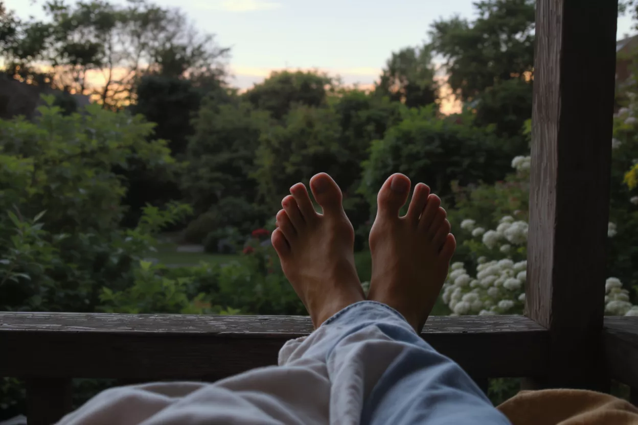 Feet resting on a wooden railing with greenery
