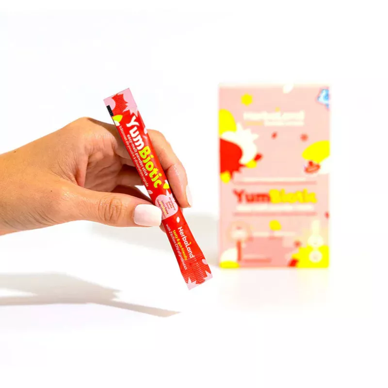 Hand holding YumBiotic red packet, health supplement, sleek design, vibrant colors, branding focus.