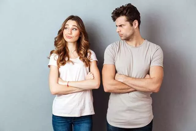 Couple in conflict with crossed arms and tense body language.