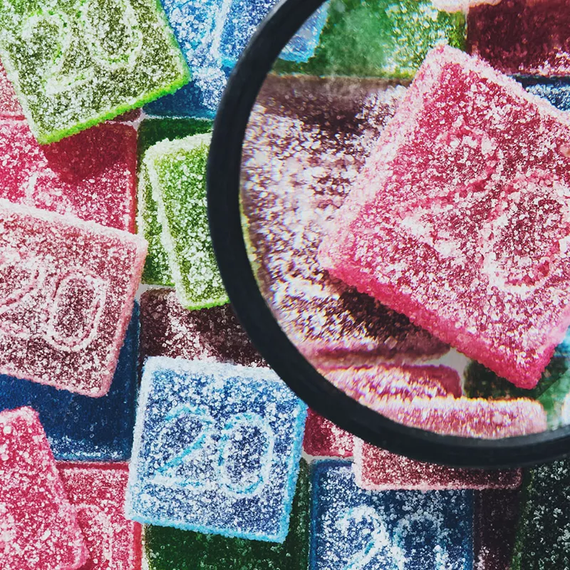Colorful sour gummy candies with number 20 imprint, magnified texture detail.