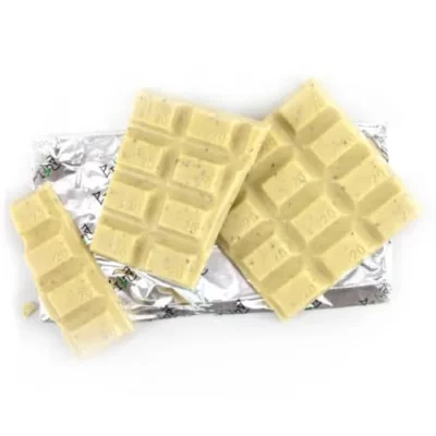 Creamy white chocolate bar, partially unwrapped and broken into pieces on a white background.