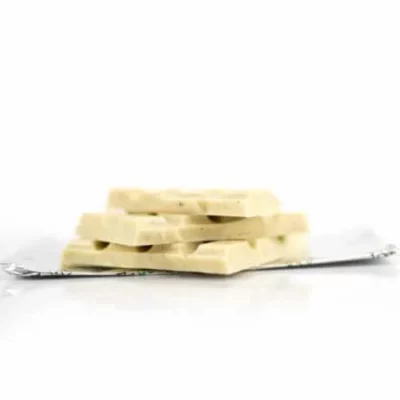 Stacked white chocolate bars with creamy texture on a shiny surface, ideal for snacking.