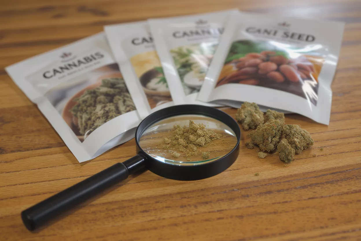 Cannabis products, magnifying glass, and kief on a wooden table.