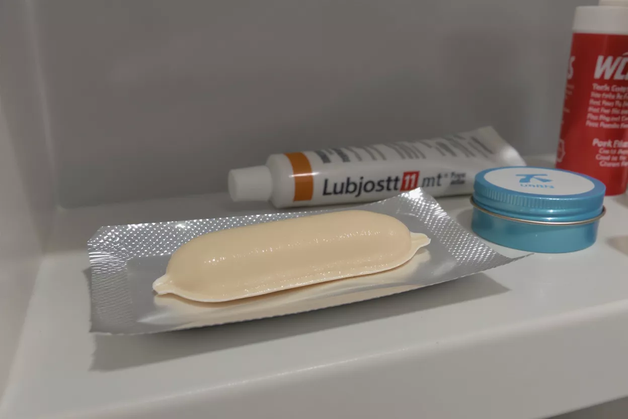An off-white suppository resting in its opened silver foil blister pack on a shelf.