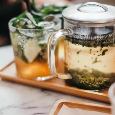 THC-infused tea brewing set with mojito-style glass on wooden tray.