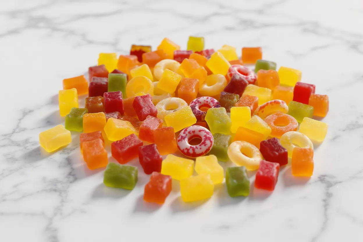 A vibrant pile of assorted gummy candies on a white marble surface.