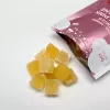 A pile of yellow gummy vitamins beside their packaging