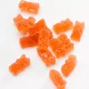 Orange gummy bear candies scattered on white background.