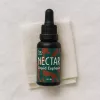 THC-infused NECTAR Liquid Euphoria bottle on textured fabric background.