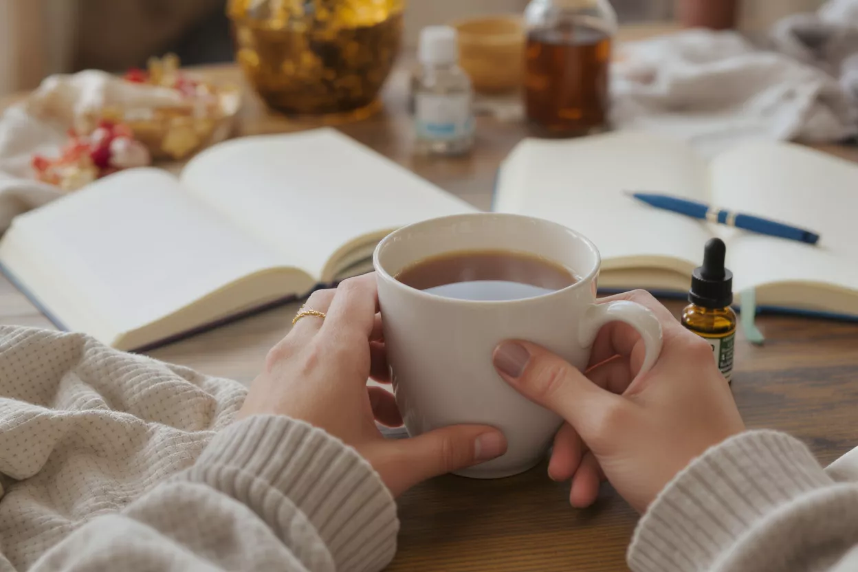 Cozy Morning Coffee and Journal Hands holding a warm mug of coffee with an open journal in the background.