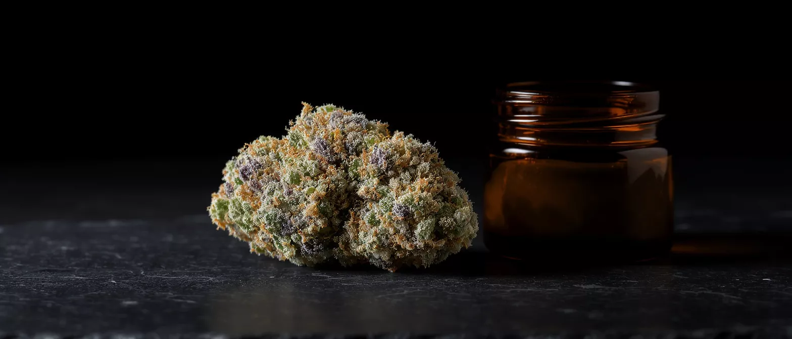 Close-up of a vibrant cannabis bud next to a small amber glass jar.